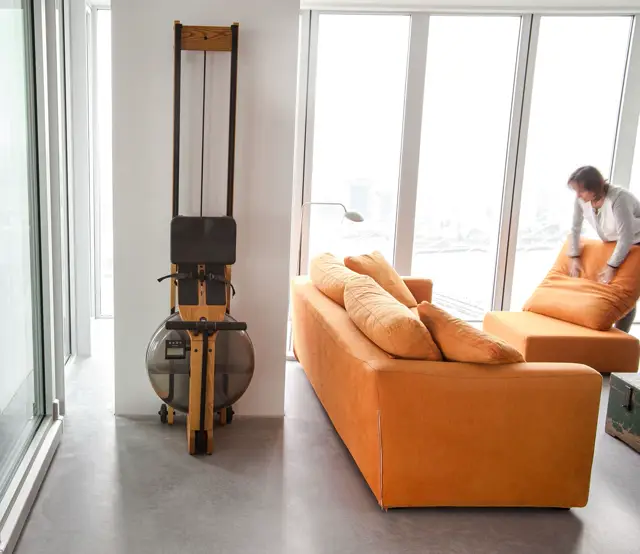 Ruime, lichte woonkamer op grote hoogte met panoramische ramen. Naadloze grijze vloer loopt ononderbroken door, geaccentueerd door modern oranje meubilair en minimalistisch interieur.