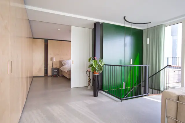 Ruim, licht loftwoning met seamless vloer, witte scheidingswand, natuurlijke houttinten en een opvallend groen glaswerk. Strak design met veel daglicht via raampartijen.