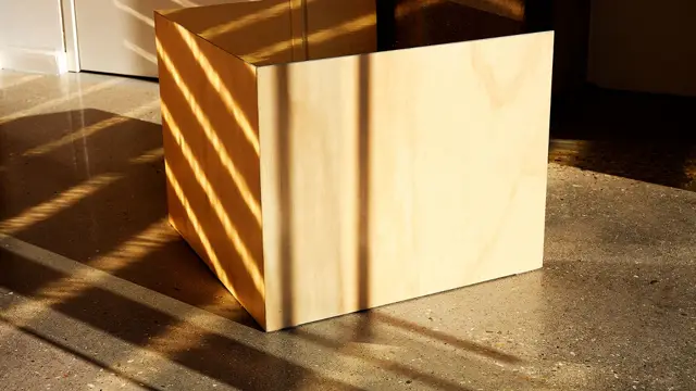 Een lichte, minimalistische naadloze wand wordt dramatisch belicht door zonlicht, waardoor zachte schaduwen ontstaan die de perfecte afwerking benadrukken.