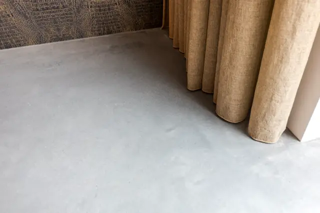 Een serene weergave van een lichte, minimalistische naadloze vloer met gerolde textielstukken in naturel tinten. De compositie benadrukt schoon design en materiaalcombinaties.
