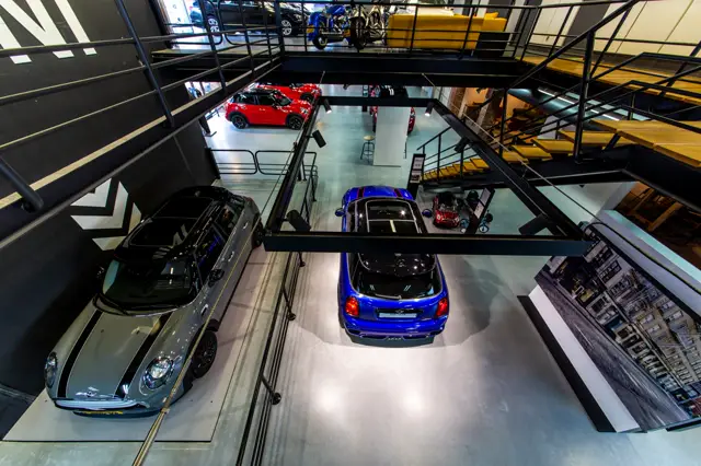 Een moderne autoShowroom met luxe voertuigen op een grote, glanzende naadloze vloer. De ruimte is helder verlicht met strakke lijnen en meerdere verdiepingen.