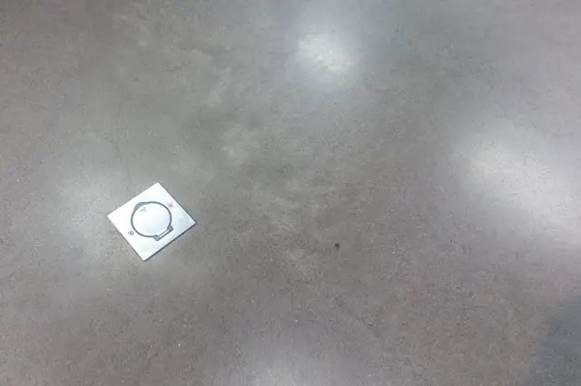 Een schoon, strak detail op een lichte naadloze vloer met perfecte afwerking. Het esthetische ontwerp benadrukt de nauwkeurigheid en kwaliteit van de afwerking.