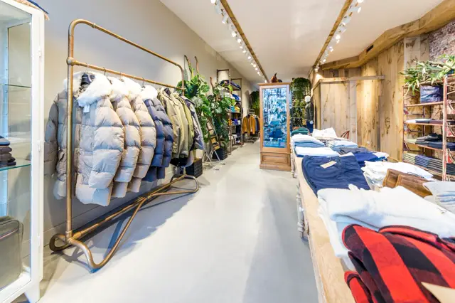 Een lichte, minimalistisch ingerichte winkelruimte met een subtiele naadloze vloer die de aandacht naar de verzameling kleding leidt. Natuurlijk licht accentueert de schone lijnen en strakke lay-out.