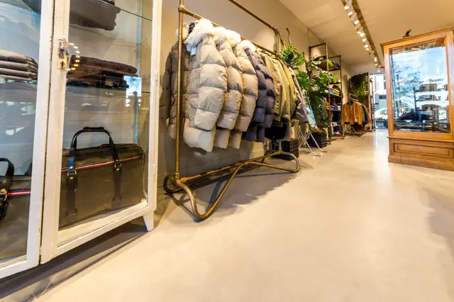Schone, moderne winkelruimte met een naadloze lichte vloer die een rustige, opgeruimde sfeer creëert. Het licht valt helder naar binnen en benadrukt de strakke lijnen van de inrichting.