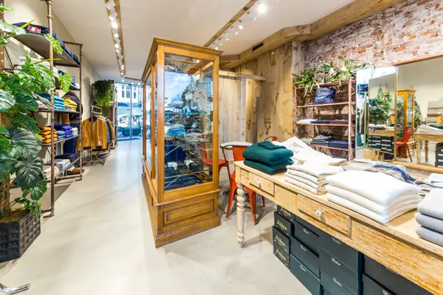 Ruime winkelruimte met een strakke, lichte naadloze vloer die het minimalistisch interieur benadrukt. De vloer zorgt voor een schoon, galerieachtig effect dat de geëxposeerde producten en houten details naar voren brengt.