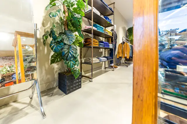 Schone, minimalistische winkelinterieur met een lichte naadloze vloer die rust en ruimtelijkheid uitstraalt. De vloer vormt een perfect neutrale achtergrond voor de gestyleerde merchandising en groeneplanten.