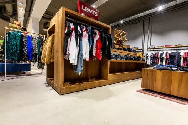 Moderne winkelruimte met grote houten displaykasten en een schone, egale naadloze vloer. Het interieur combineert natuurlijke houtaccenten met strakke lijnen en professionele verlichting.