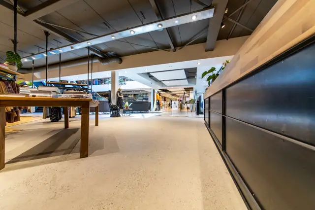 Grootschalige, lichte naadloze vloer in een modern winkel- en retailruimte met natuurlijke inval van licht, strakke lijnen en minimalistische inrichting.