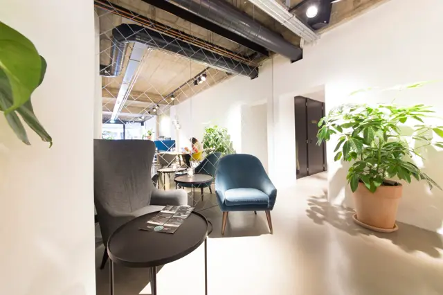 Een moderne, lichte werkruimte met schone naadloze vloer, minimalistisch ingericht met designmeubels en veel groen. De ruimte ademt rust en professionaliteit uit.