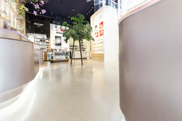 Moderne retail-omgeving met een strakke, lichte naadloze vloer die naadloos aansluit op gebogen wandelementen. De ruimte ademt minimalisme en hoogwaardige afwerking uit.
