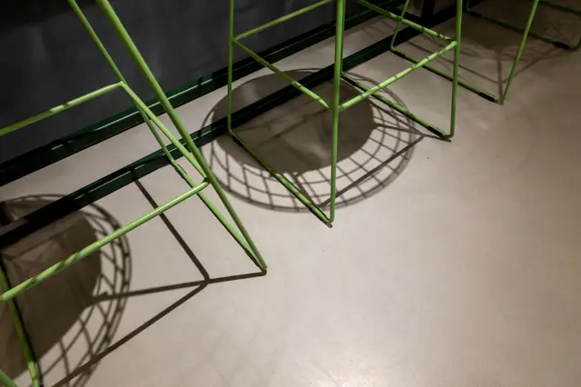 Lichte, gladde naadloze vloer met strakke geometrische schaduwen van moderne stoelen. Schoon, onberispelijk oppervlak met perfecte vlakheid en rustgevende uitstraling.