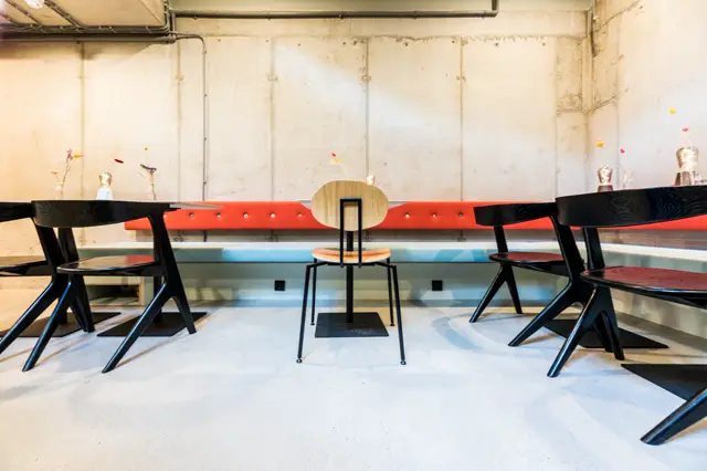 Een strak ingerichte bedrijfsruimte met een lichte naadloze vloer, moderne stoelen en kleurig design accent op de achterwand. De vloer creëert een schoon, samenhangend geheel.
