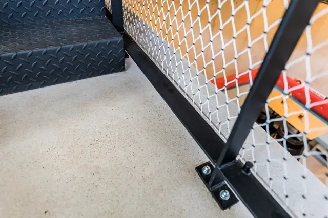 Detailshot van een lichte naadloze vloer in moderne hotelomgeving, met zwarte afwerkingselementen en metalen constructies. De vloer toont een neutrale, verfijnde uitstraling.