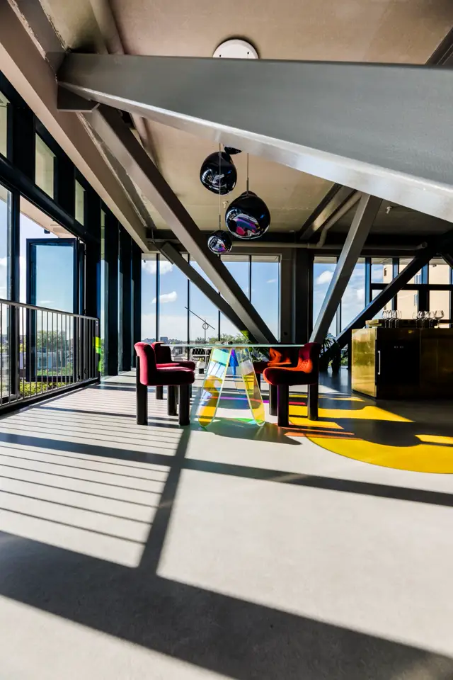 Ruime, licht overstroomde woonruimte met strakke naadloze vloer, grote raampartijen en een minimalistisch interieur. Architectonische staalconstructie creëert een industrieel-luxe sfeer.