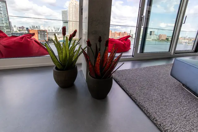 Luxe penthouse-interieur met glad afgewerkte vloer, minimalistische decoratie en spectaculair uitzicht over water en skyline. Strakke lijnen en verfijnde kleurkeuzes creëren een vorstelijke sfeer.