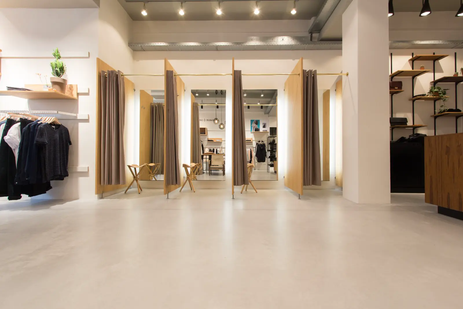 Moderne retail space met minimalistische inrichting, grote spiegels, houten accenten en een lichte naadloze vloer die de ruimte airy en opgeruimd doet voelen. Perfecte belichting en strakke lijnen.