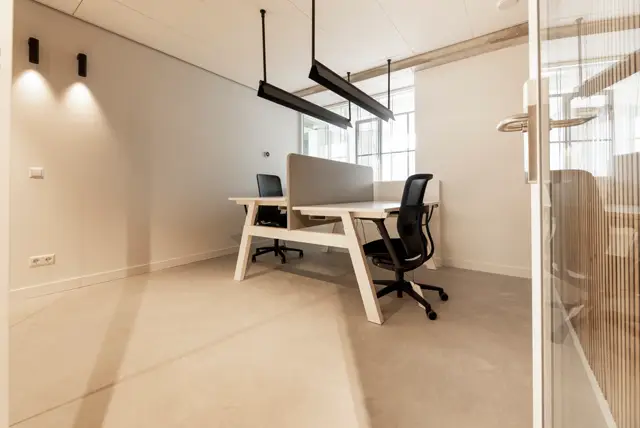 Strak ingericht kantoorinterieur met een uniforme, lichte naadloze vloer die het hele ruimte samen brengt. Clean design met natuurlijk licht, moderne verlichting en grijstinten créeert een professionele, rustgevende werkplek.
