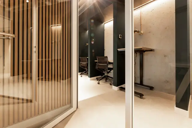 Schoon, strak kantoorinterieur met lichte naadloze vloer, houten latten-scheidingswand en minimalistisch design. Perfecte afwerking met scherpe lijnen en professionele uitstraling.