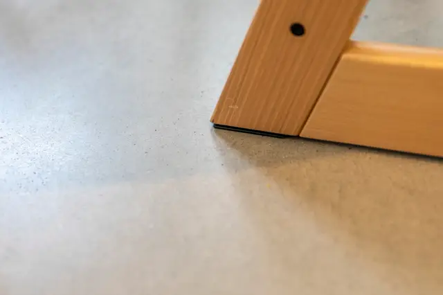 Detailshot van een lichte naadloze vloer met perfect aansluitend houten element. De minimale afwerking en scherpe overgang demonstreren de nauwkeurigheid van de craftmanship.