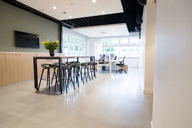 Strakke, lichte bedrijfsomgeving met een grootvlakkige naadloze vloer in licht naturel. De ruimte ademt luxe en functionaliteit uit met minimalistisch design, veel daglicht en hoogwaardige afwerking.