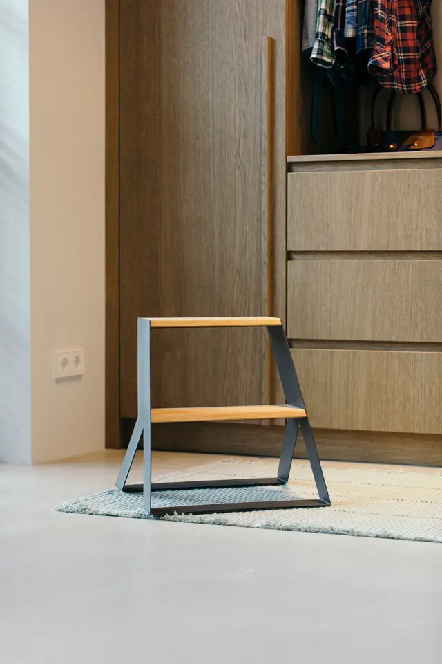 Schoon, licht slaapkamerinterieur met strakke houten inbouwkasten, geometrische trap en naadloze vloer in warm grijs. Perfecte ordening en scherpe lijnen.