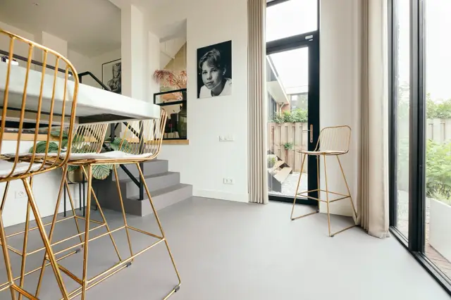 Ruime, licht ingedeelde hal met een moderne naadloze vloer in warm grijs. Het interieur combineert eigentijdse designelementen met een open, opgeruimde uitstraling.