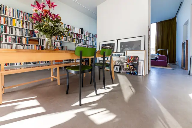 Moderne bibliotheekruimte met een subtiele, geslepen naadloze vloer in warme taupe-tint. Het oppervlak reflecteert zacht licht en benadrukt de strakke, opgeruimde architectuur van deze kunstzinnige woonruimte.