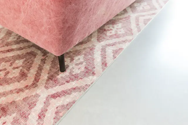Een elegante roze stoel staat op een lichte, naadloze vloer met subtiel patroon. De compositie toont het naadloze overgang tussen vloer en het minimalistisch interieur.