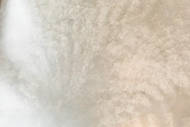 Detailopname van een naadloze vloer met subtiele textuur in warm beige- en grijstinten. Het oppervlak oogt rustig, uniform en perfect afgewerkt.