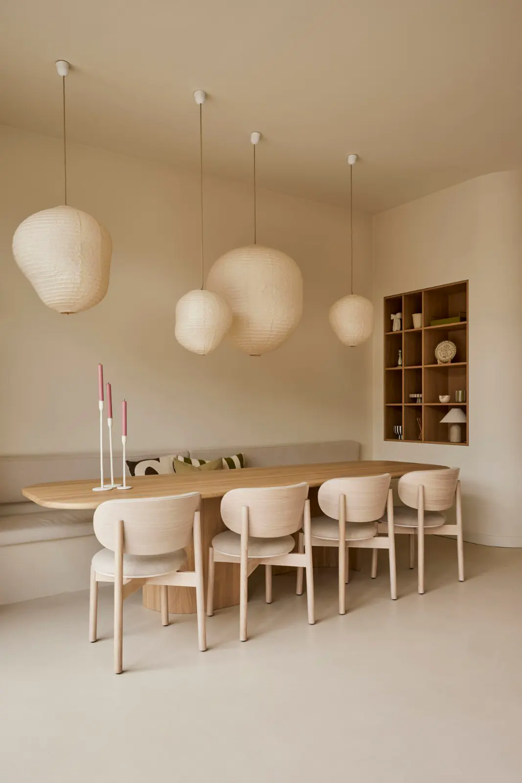 Een serene eetkamer met natuurlijke houttinten, waarin een schone naadloze vloer en wanden de perfecte backdrop vormen voor scandinavisch design met hangende lampjes en opgeruimd meubilair.