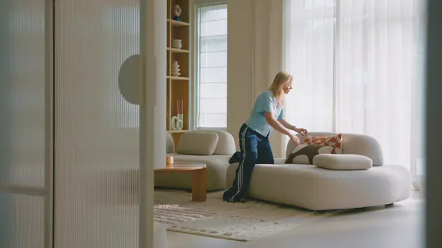 Ruim, minimalistisch ingerichte woonkamer met grote ramen, zachte natuurlijke lichtinval en een homogene, strakke naadloze vloer. De ruimte ademt luxe en rust uit door de samenhangende afwerking.