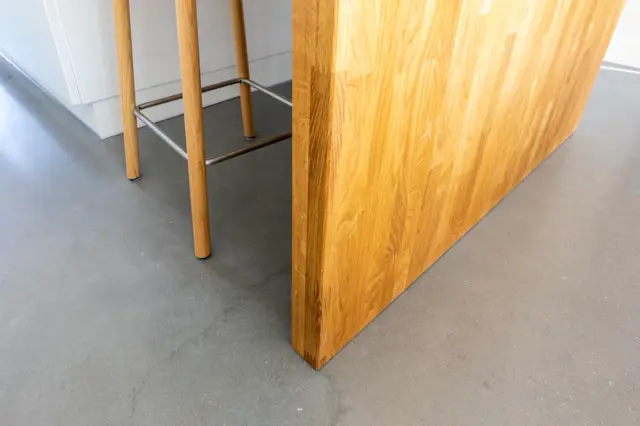 Een minimalistische ruimte met een gladde grijze naadloze vloer en warme houten wandelementen. Strakke lijnen en verfijnde materiaalcombinatie creëren een evenwichtig, design-gericht geheel.