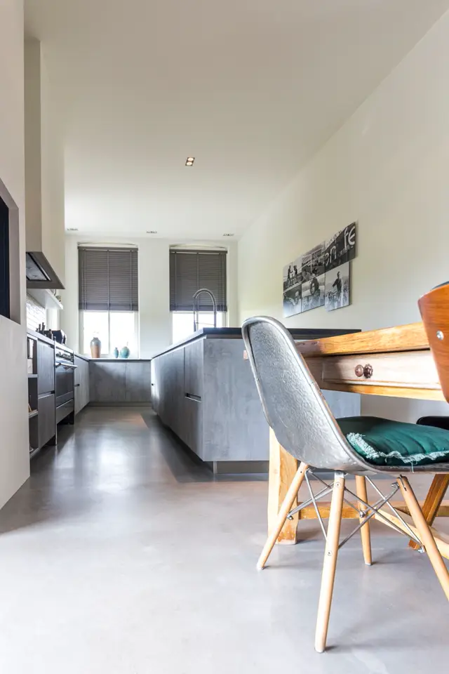 Ruim, licht interieur met grijze naadloze vloer die keuken en living-area verbindt. Strakke grijze keukenkasten, houten accenten en minimalistisch ingericht met hedendaagse meubelen.