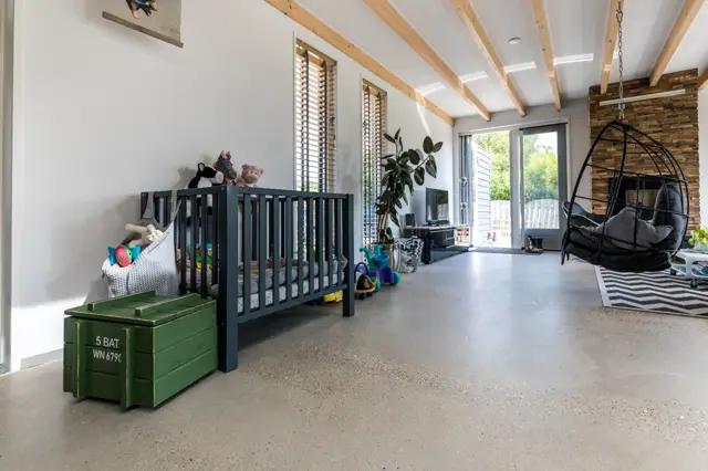 Ruime, lichte kinderkamer met naadloze vloer en open architectuur. Houten balkenplafond en grote raampartijen zorgen voor een speelse, aangenaam proportioneerde ruimte.