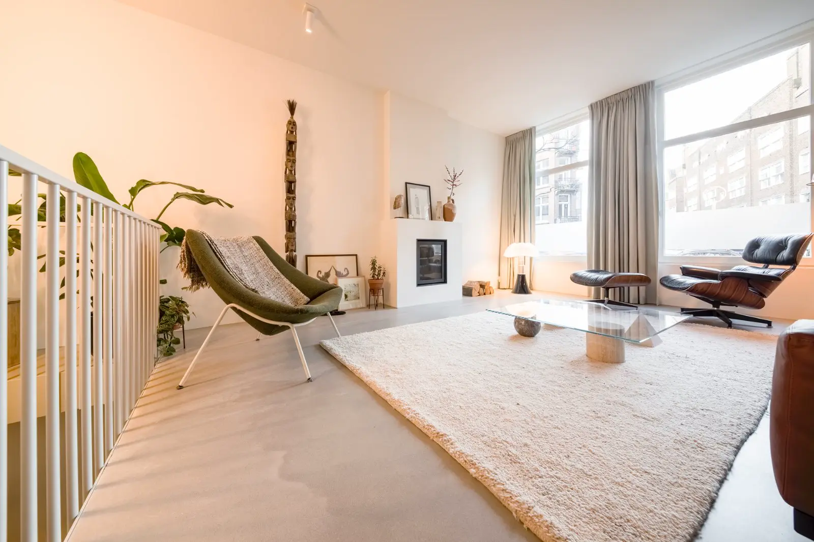 Ruime, lichte woonkamer met een naadloze lichte vloer die naadloos overgaat in verschillende ruimtes. Minimalistisch ingericht met designmeubels, grote ramen en een warme, serene sfeer.